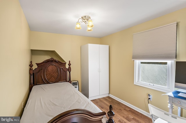 bedroom with a chandelier, baseboards, and wood finished floors