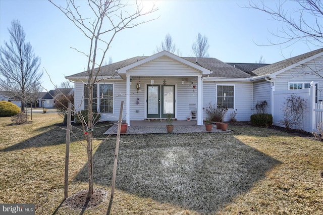 view of front of home featuring a front lawn, fence, covered porch, and roof with shingles