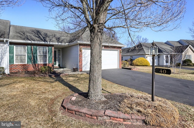 view of front facade featuring aphalt driveway, brick siding, a garage, and roof with shingles