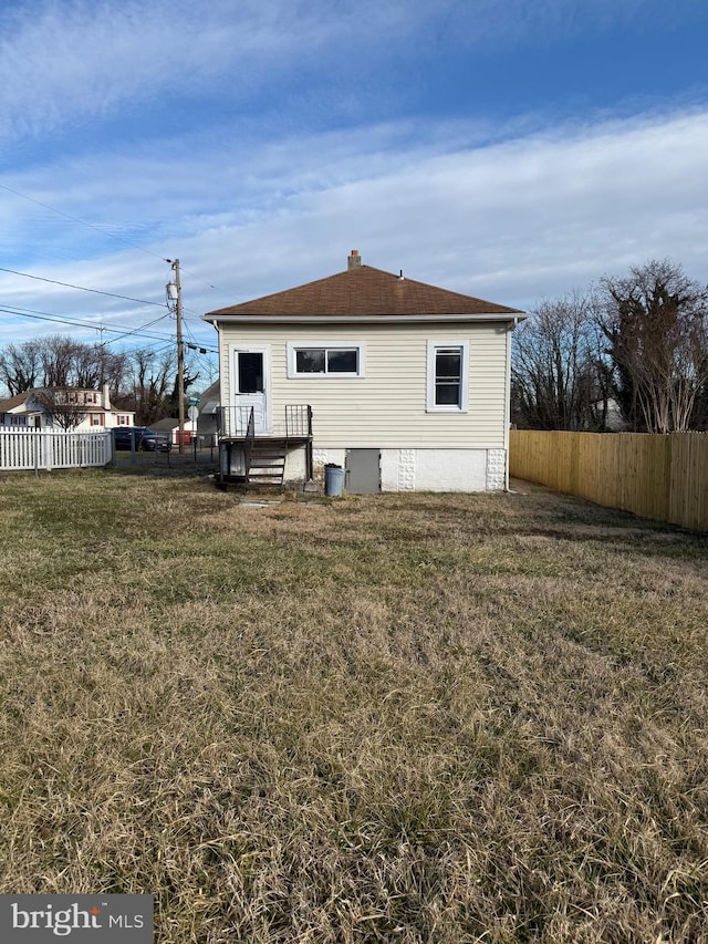 239 Midland, Brooklyn, MD 21225 - back of house featuring a chimney, a shingled roof, fence, and a yard
