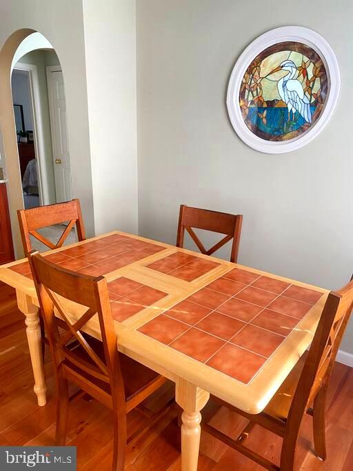 dining area with arched walkways and wood finished floors