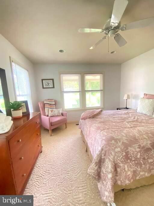 bedroom with multiple windows, light carpet, and ceiling fan