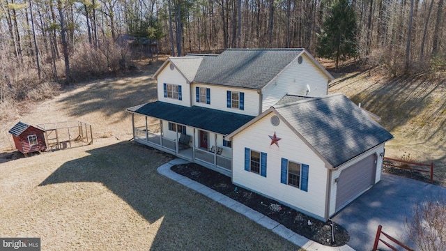 view of front of property with an attached garage, covered porch, driveway, and roof with shingles