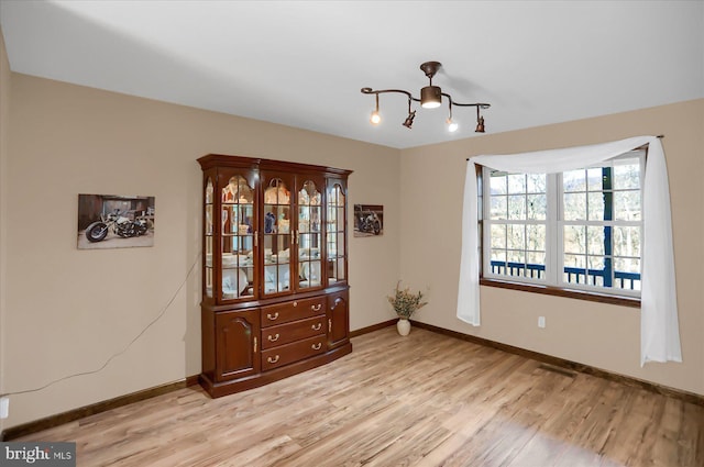 interior space featuring light wood finished floors, an inviting chandelier, and baseboards