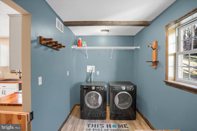 laundry room with visible vents, separate washer and dryer, baseboards, and a sink