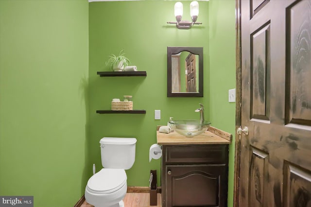 bathroom featuring toilet, vanity, and baseboards