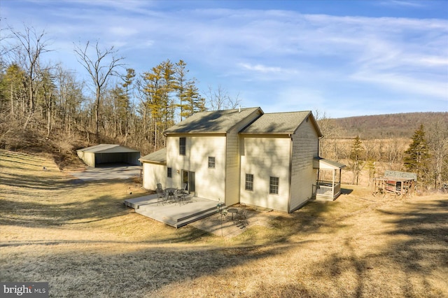 rear view of property featuring a wooded view and an outdoor structure