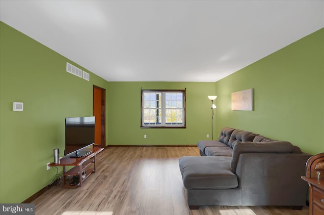 living room with visible vents, baseboards, and wood finished floors