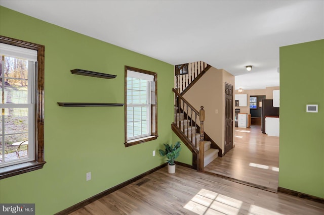 spare room featuring stairs, visible vents, wood finished floors, and baseboards