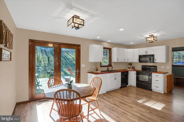 kitchen with light wood-type flooring, black appliances, a sink, white cabinetry, and recessed lighting