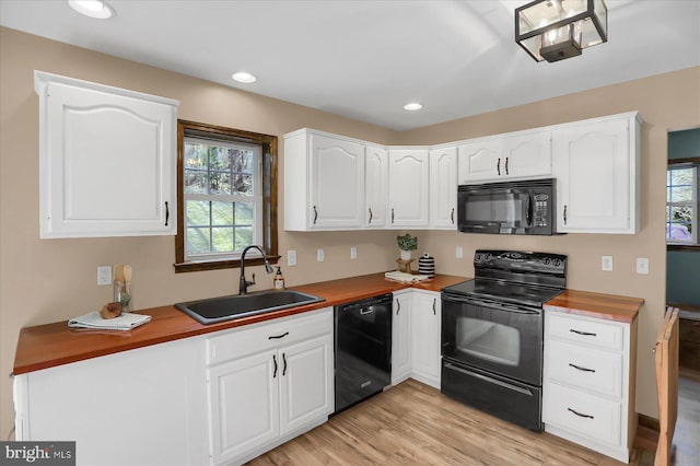 kitchen with black appliances, a sink, white cabinets, light wood finished floors, and wooden counters