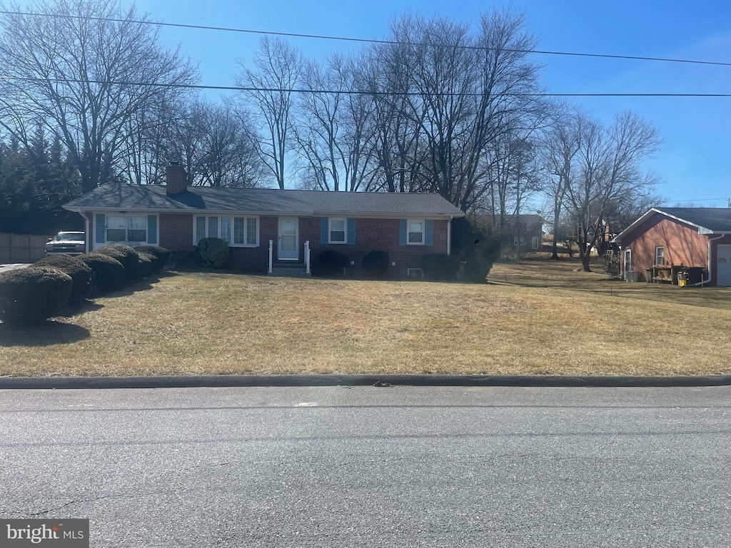 view of front of house with brick siding, a chimney, and a front lawn