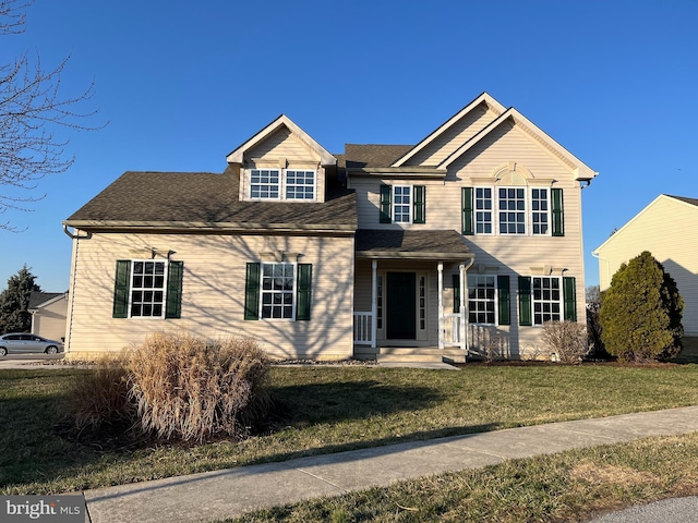 traditional home featuring a shingled roof and a front lawn