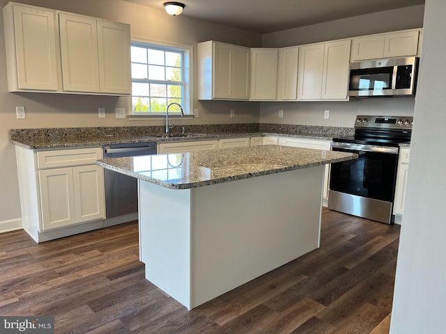 kitchen with dark wood-style flooring, appliances with stainless steel finishes, white cabinetry, and a sink