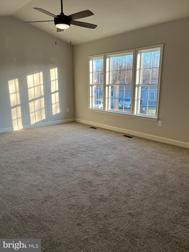 carpeted spare room with visible vents, a ceiling fan, baseboards, and vaulted ceiling