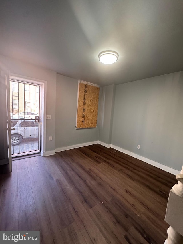 spare room featuring baseboards and dark wood-style flooring