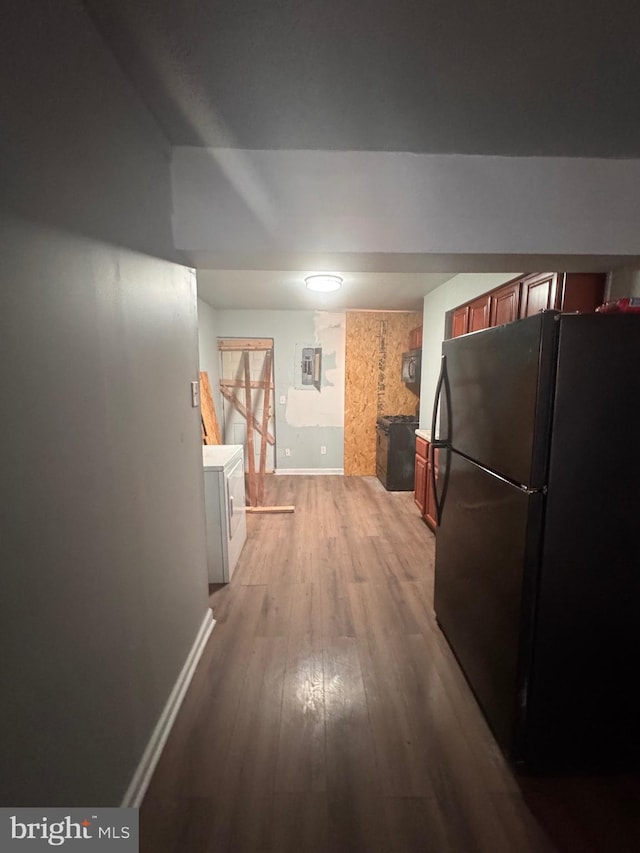 hall with washer / dryer, baseboards, and light wood finished floors