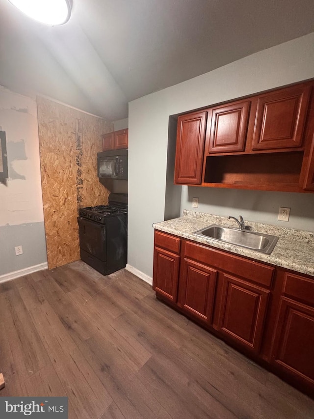 kitchen featuring dark wood-style floors, lofted ceiling, a sink, black appliances, and light countertops