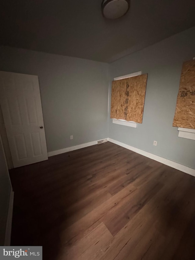 spare room featuring visible vents, dark wood-style floors, and baseboards