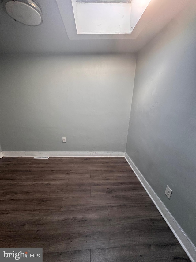 spare room featuring baseboards and dark wood-type flooring