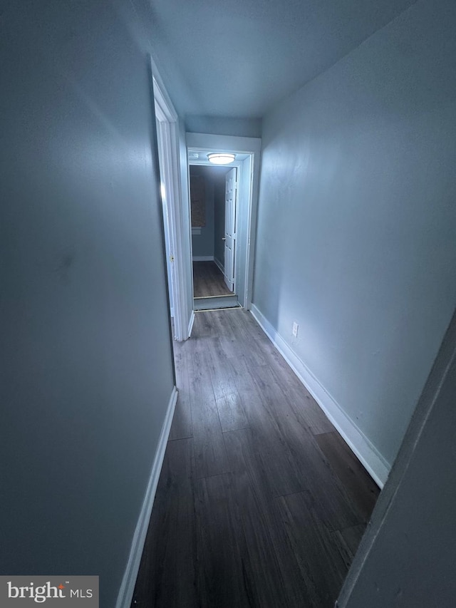 hallway with dark wood-type flooring and baseboards