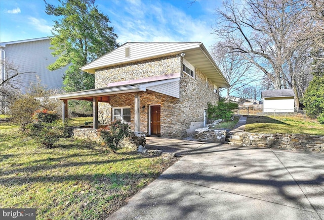 view of front facade with stone siding, covered porch, a front yard, and fence