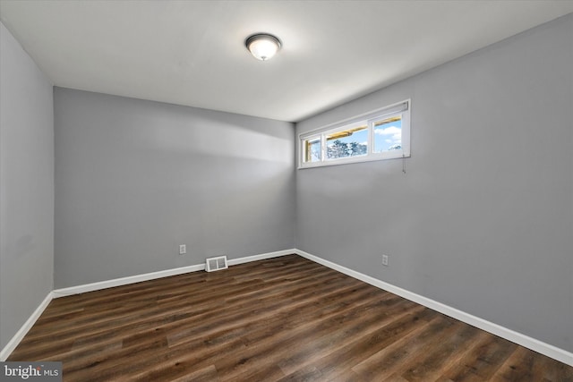 unfurnished room featuring visible vents, baseboards, and dark wood-style flooring