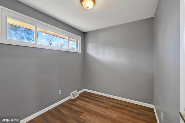 spare room with dark wood-type flooring, baseboards, and visible vents