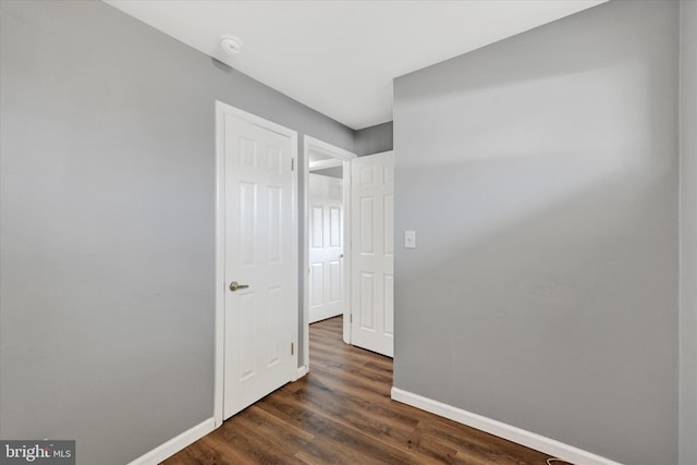 unfurnished room featuring baseboards and dark wood-style flooring