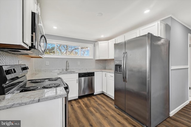 kitchen with a sink, light stone counters, dark wood-style floors, white cabinetry, and appliances with stainless steel finishes