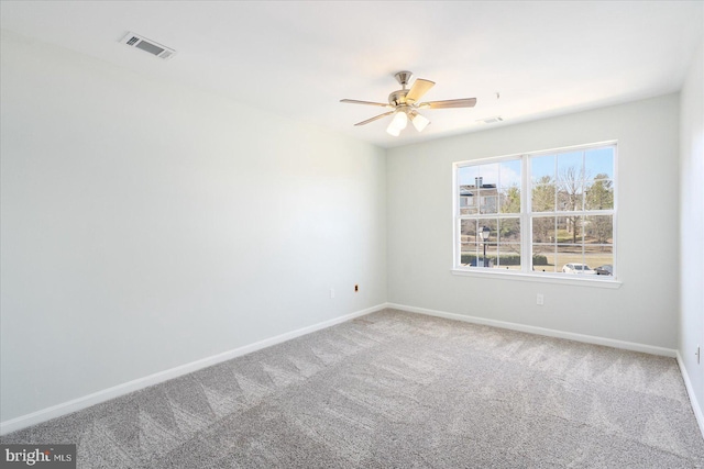 carpeted empty room with visible vents, baseboards, and a ceiling fan