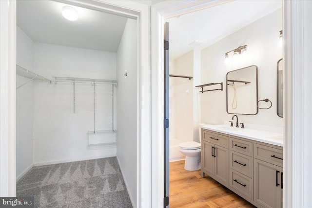 full bath with a walk in closet, toilet, and vanity