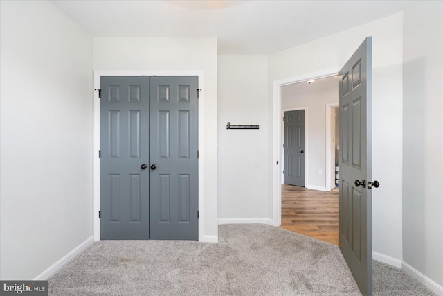 unfurnished bedroom featuring light carpet, baseboards, and a closet