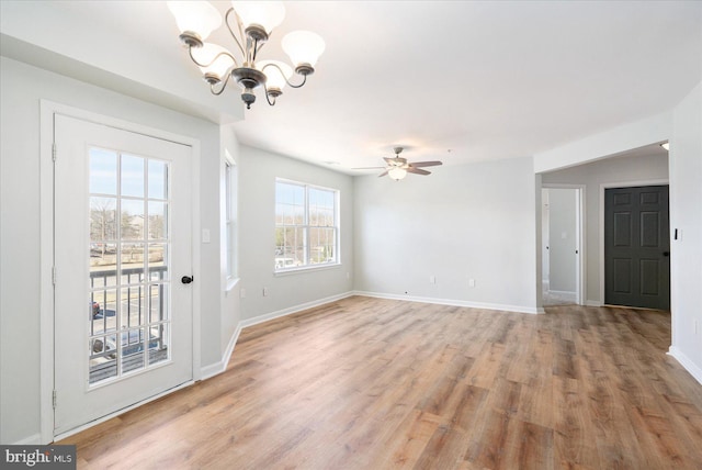 interior space with ceiling fan with notable chandelier, baseboards, and light wood-type flooring