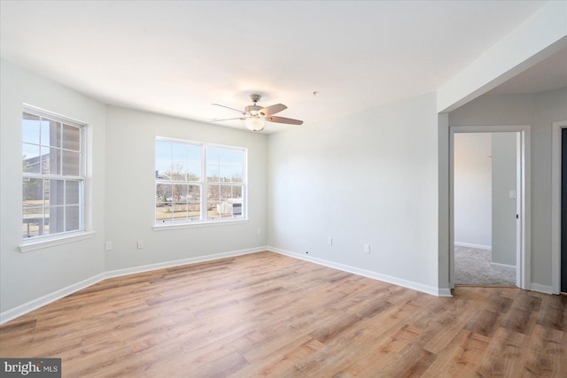 spare room with ceiling fan, light wood-type flooring, and baseboards