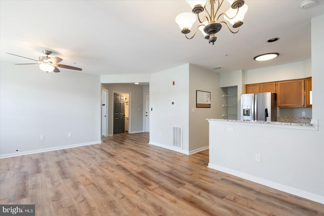 kitchen with brown cabinetry, stainless steel fridge with ice dispenser, visible vents, and baseboards