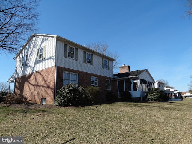 exterior space featuring brick siding, a yard, and a sunroom