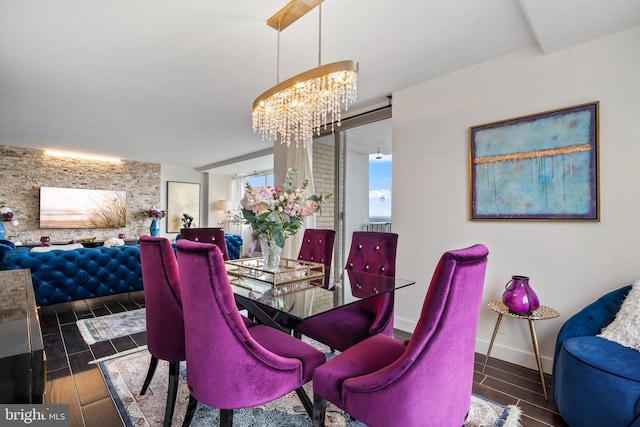 dining area featuring an accent wall, an inviting chandelier, baseboards, and wood tiled floor