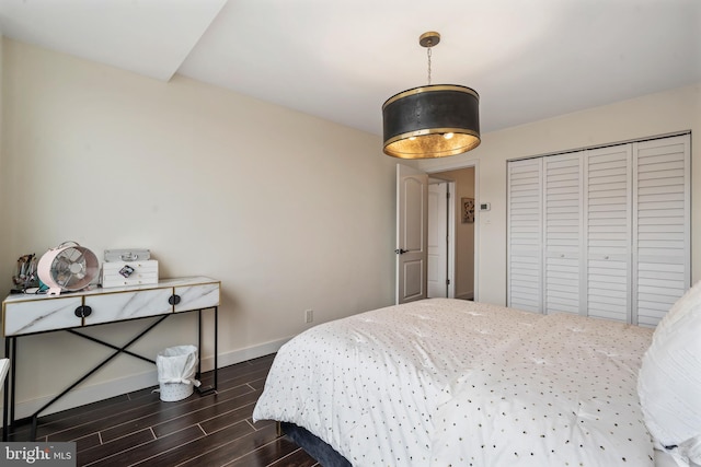 bedroom featuring a closet, baseboards, and dark wood-style flooring