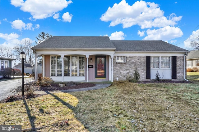 ranch-style home with a front yard, brick siding, and a shingled roof