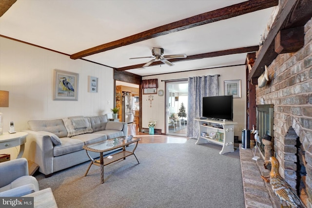 living room featuring beam ceiling, a brick fireplace, carpet flooring, and ceiling fan