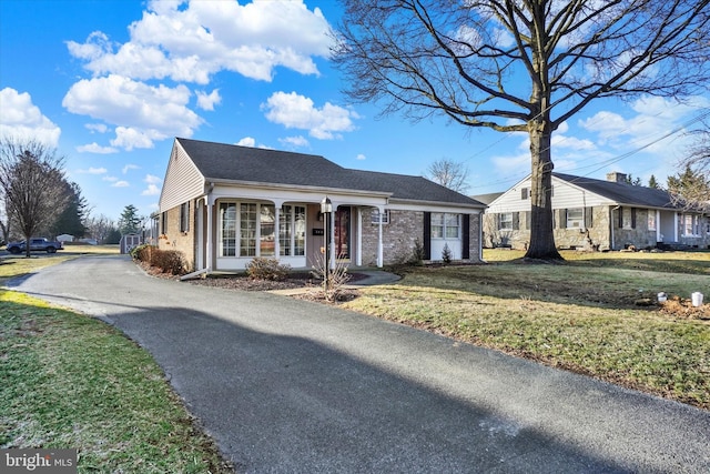 ranch-style home featuring a front yard, brick siding, and aphalt driveway