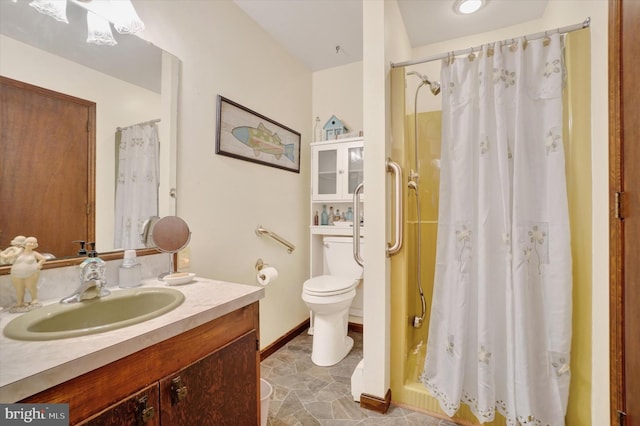 bathroom with baseboards, toilet, a stall shower, and vanity