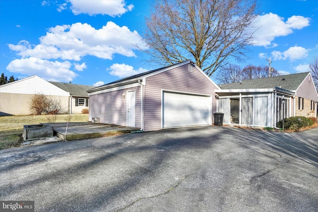 view of side of home featuring aphalt driveway, a garage, and an outdoor structure