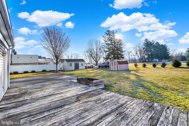 wooden terrace featuring a yard, a storage unit, an outdoor structure, and fence