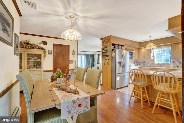 dining area featuring visible vents, light wood-type flooring, baseboard heating, and a chandelier