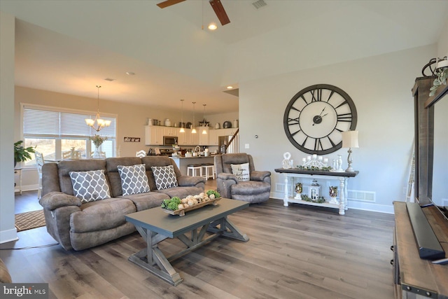 living area featuring wood finished floors, visible vents, recessed lighting, stairs, and ceiling fan with notable chandelier