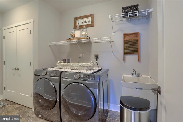 clothes washing area featuring laundry area, stone finish floor, baseboards, and independent washer and dryer