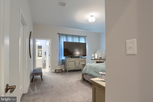 carpeted bedroom with ensuite bath, baseboards, and visible vents