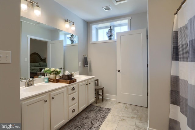 ensuite bathroom with visible vents, double vanity, a sink, marble finish floor, and connected bathroom